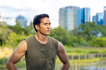 Portrait of Asian man in sportswear jogging exercise at public park in summer morning. Healthy guy athlete enjoy outdoor activity lifestyle sport training fitness running workout in the city.