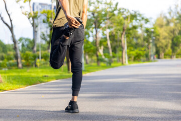 Asian man in sportswear stretching body and warm up before jogging exercise at public park in the morning. Healthy guy athlete enjoy outdoor lifestyle sport training running workout in the city.