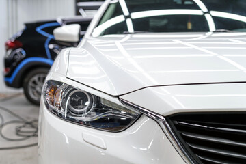 Protective film sticker on the headlight of a white car. Car detailing studio