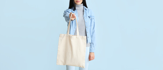 Young woman with eco bag on light blue background