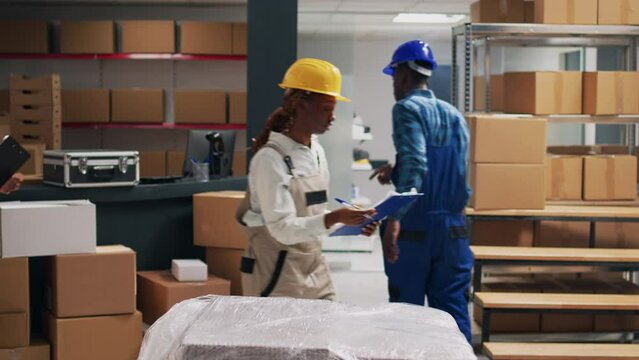 Team of people planning shipment with products in boxes, checking inventory list on papers for distribution service. Man and woman discussing about stock logistics and merchandise.