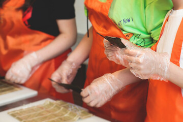Group of children in a cooking class, kids preparing asian style food in the kitchen together, kids...