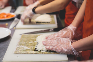 Group of children in a cooking class, kids preparing asian style food in the kitchen together, kids in aprons learn cooking on master class, chef uniform, hands in gloves