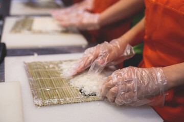 Group of children in a cooking class, kids preparing asian style food in the kitchen together, kids in aprons learn cooking on master class, chef uniform, hands in gloves
