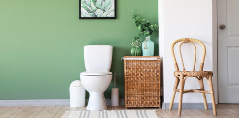 Interior of modern bathroom with toilet bowl and wicker basket