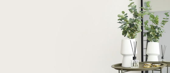 Vase with eucalyptus, reed diffuser and aroma candles on table near mirror in light room. Banner...