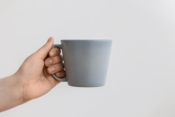 Woman holding grey cup on light background