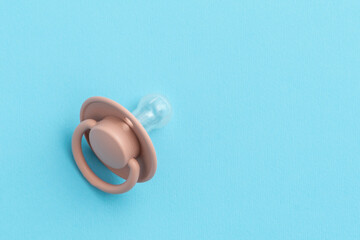 Pink baby pacifier on blue background with copy space, top view, flat lay. Newborn concept