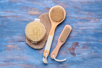 Massage brushes and glove on color wooden background