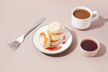 Plate with delicious cottage cheese pancakes, strawberry jam and cup of coffee on color background