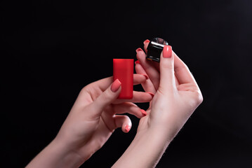 Red color vape pod system with replaceable cartridges in female hands isolated on black background....