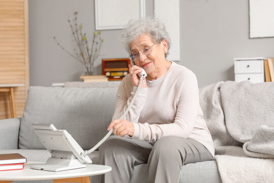 Senior Woman Talking By Telephone On Sofa At Home