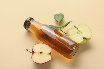Glass bottle of fresh apple cider vinegar and fruits on beige background