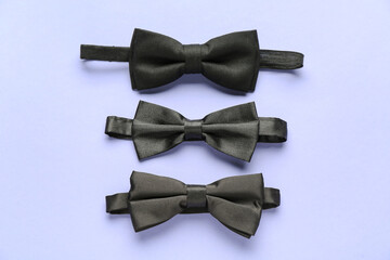Set of black bow ties on color background