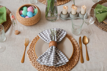 Fototapeta na wymiar Beautiful Easter table setting with eggs and candles in dining room, closeup
