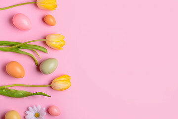 Composition with painted Easter eggs and spring flowers on pink background