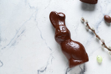 Chocolate Easter bunny with eggs and willow branch on grunge background