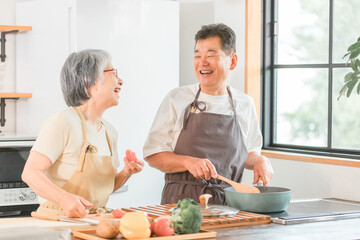家のキッチンで料理を作るシニア・高齢者夫婦（自炊・手料理）
