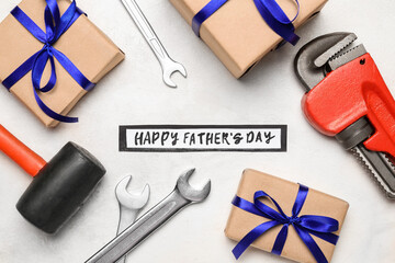 Composition with construction tools and gifts for Father's Day celebration on light background