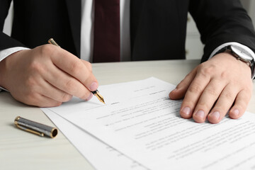 Notary signing document at wooden table, closeup