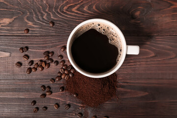 Cup of coffee with powder and beans on dark wooden background