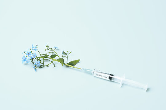 Syringe and flowers on blue background, beauty injections creative concept