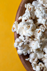 Tigela de madeira com pipoca e fundo amarelo