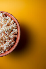 Tigela de madeira com pipoca e fundo amarelo