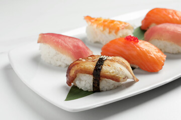 Plate with delicious nigiri sushi on white table, closeup