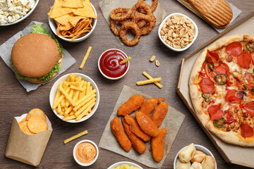 French fries, chips and other fast food on wooden table, flat lay