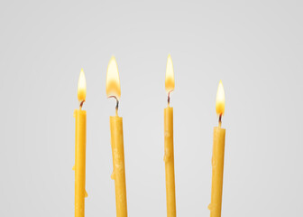 Many burning church candles on light background