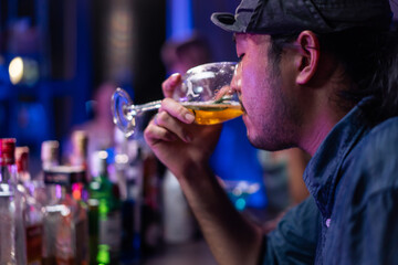 Asian depression man feeling heart broken and drinking beer in a bar.