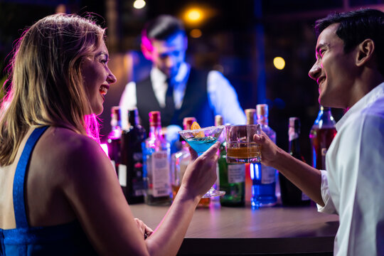 Beautiful young couple having fun, drinking alcohol cocktail in a bar.