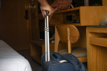 Hand of a person carrying suitcase trolley inside a room. Hospitality, luggage, OYO, booking,...