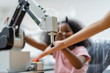 Kid female teen child enjoy Machine Learning Robot arm is Moving Under Control robot at technology class, stem education robot arms for digital automation software for artificial intelligence ai