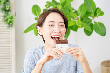 家でチョコレートを食べる女性