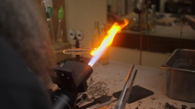 Glass blowing artist increases flame to melt glass for artwork