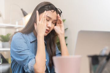 Exhausted, stressed asian young business woman, girl  working, took off glasses, have a headache suffer on hard work while use laptop computer at office. Overtime job, problem people. Health care.