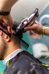 Fototapeta na wymiar barber with comb cutting hair with razor for latino customer