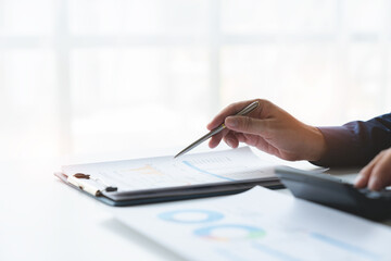 Fototapeta premium Investing young businessman accountant using calculator for income-expense calculation and planning pointing to database showing graph chart real estate business income finance and tax system concept