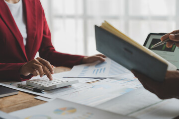 Group of businessmen, investors brainstorming financial reports with calculators to calculate income, taxes, accounting from graphs, growth charts and making notes in a notebook for meeting reminders