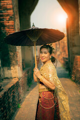 beautiful asian woman wearing thai tradition clothes holding  bamboo umbrella standing in old temple at ayutthaya world heritage site of unesco central of thailand