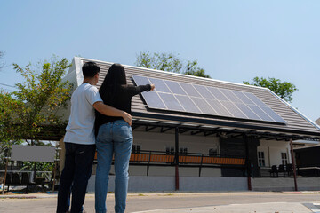 Family uses renewable energy system with solar panel. Rear View Of A Young Couple Standing In Front...