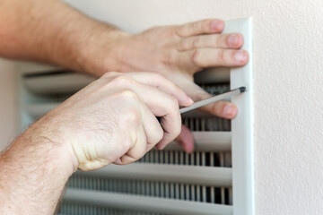 Obraz premium Male hand with a screwdriver, close-up. Repair of the ventilation system in the building.