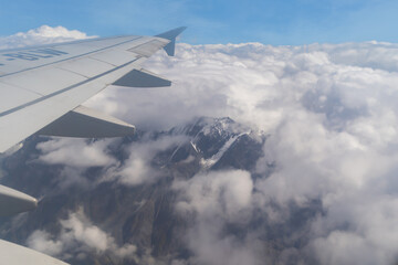 A wing of an airplane jet. The mountain hills view in Pakistan from the window in traveling and transportation concept. Nature landscape background.