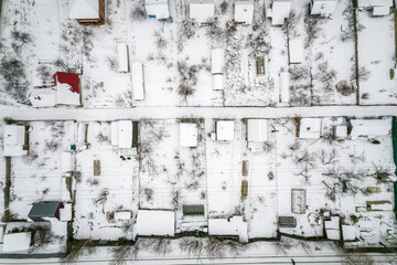 Aerial view of coniferous winter forest and a small houses.. Flying above frozen trees and snow...