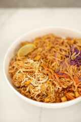 Close Up of White Ceramic Bowl of Tofu Pad Thai with Lime Slice on Kitchen Counter Top