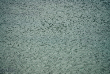 Texture of dark green calm water of lake. Meditative ripples on water surface. Nature minimal background of deep green lake. Natural backdrop of clear dark turquoise water. Full frame of lake fragment