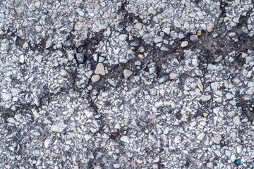 Macro photograph of weathered blacktop asphalt paving surface with stones and cracks making a great textured industrial background image with copy space. 