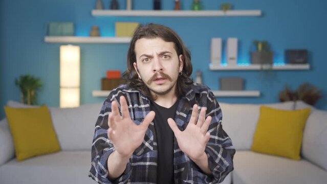 Man looking at camera with funky facial expression and gestures.
Man looking at camera is afraid. It's like something is coming over him and he's protecting himself from them.
